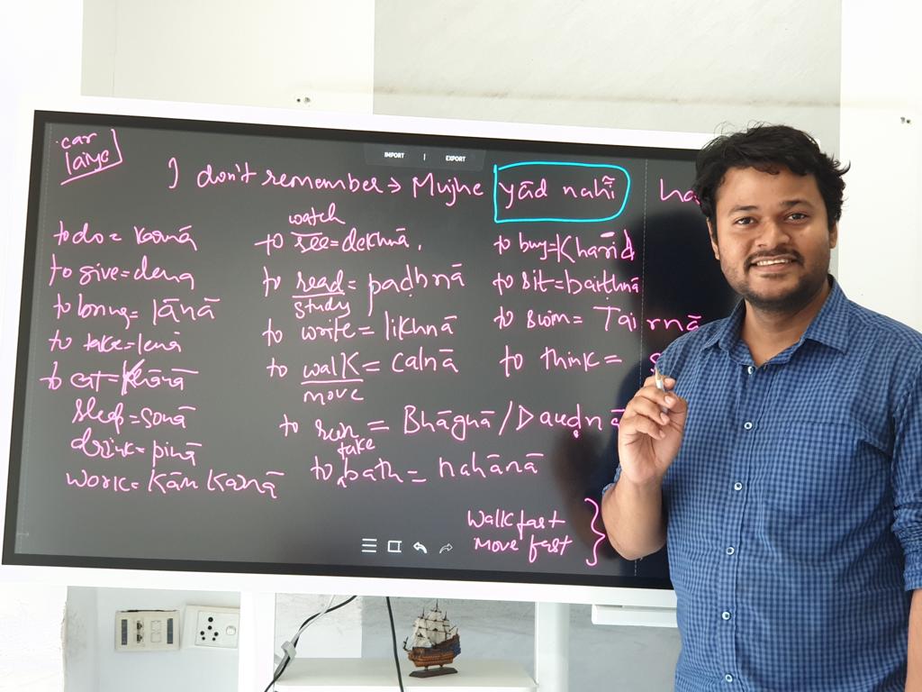 Vivek teaching Hindi in front of a lesson board